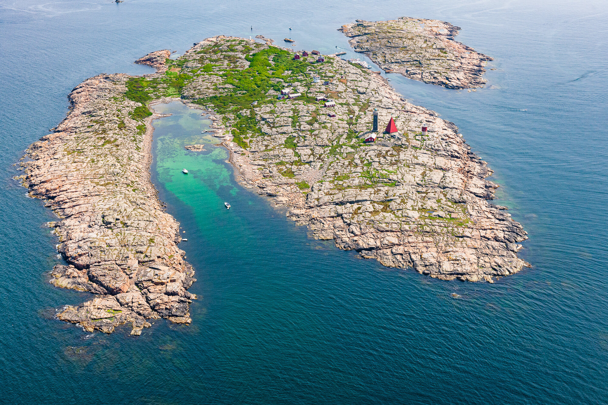 Deltagare i Ribtours-overaller som tävlar i en trekamp på en skärgårdsö medan en Ribtours RIB-båt ligger i närheten.